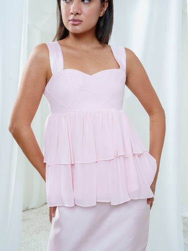 The Cascade Blouse in light pink, a silk peplum top with a sweetheart bodice and tiered georgette below.