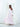 Movement view of the Vesper Dress in light pink, showing the georgette sleeve falling free of the open shoulder.