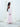 Side view of the Vesper Dress in light pink, showing the georgette sleeve falling free of the open shoulder.