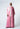 A woman wearing Nicilian’s Elle Abaya in Sachet Pink regenerative silk twill, featuring a front bow tie, Barely Pink georgette cuffs, and a matching Barely Pink shayla.