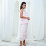 The Cascade Blouse and Cascade Skirt in light pink worn as a set, a tiered silk top above a tiered midi skirt.