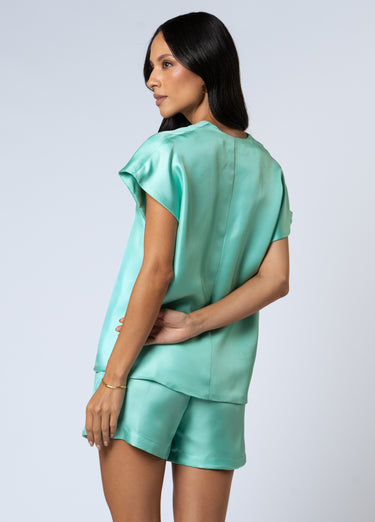 Back view of wearing Nicilian’s Aura Blouse and San Diego Shorts in Opal — a matching silk set made from regenerative silk twill, featuring a front-pleated top and adjustable tie-waist shorts.