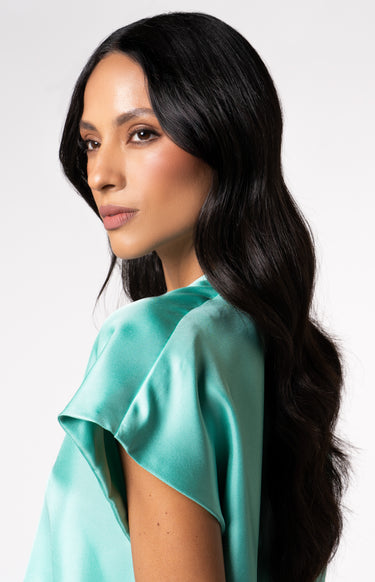 Side detail shot of model wearing Nicilian's Aura Blouse in Opal — a regenerative silk top with cap sleeves, front pleat, and V-neckline.