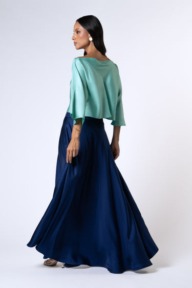 Back shot of a model wearing the Nicilian Yacht Blouse in Opal and Site Skirt in Beacon Blue, both crafted from regenerative silk twill. This full-length luxury set blends modest elegance with flowing, structured design.