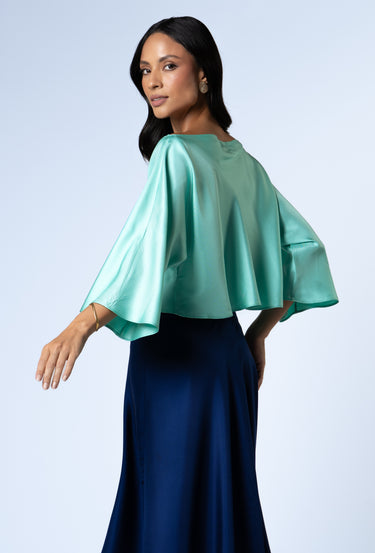 In motion side shot of a model wearing the Nicilian Yacht Blouse in Opal and Site Skirt in Beacon Blue, both crafted from regenerative silk twill. This full-length luxury set blends modest elegance with flowing, structured design.